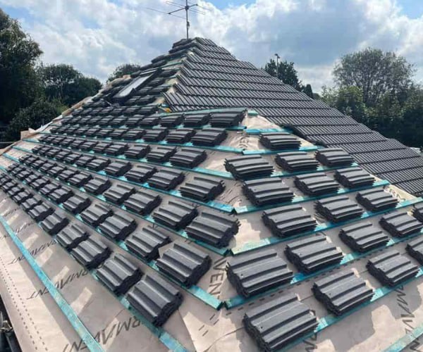 This is a photo of a new hip roof being installed. New felt, battens, and grey tiles have been installed, also a new velux window. Works carried out by LNM Roofing Featherstone