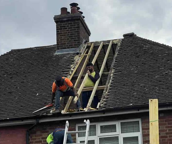 This is a photo of a roof repair being carried out. A section of the roof has been stripped and two roofers are replacing the rafters. Works being carried out by LNM Roofing Featherstone